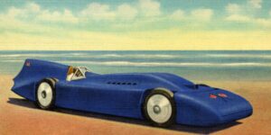 Vintage postcard illustration of a streamlined blue land-speed racing car on the hard-packed sands of Daytona Beach, capturing the early motorsports era that established Volusia County as the birthplace of speed and continues to inspire writers drawn to Florida’s racing history and coastal legend.